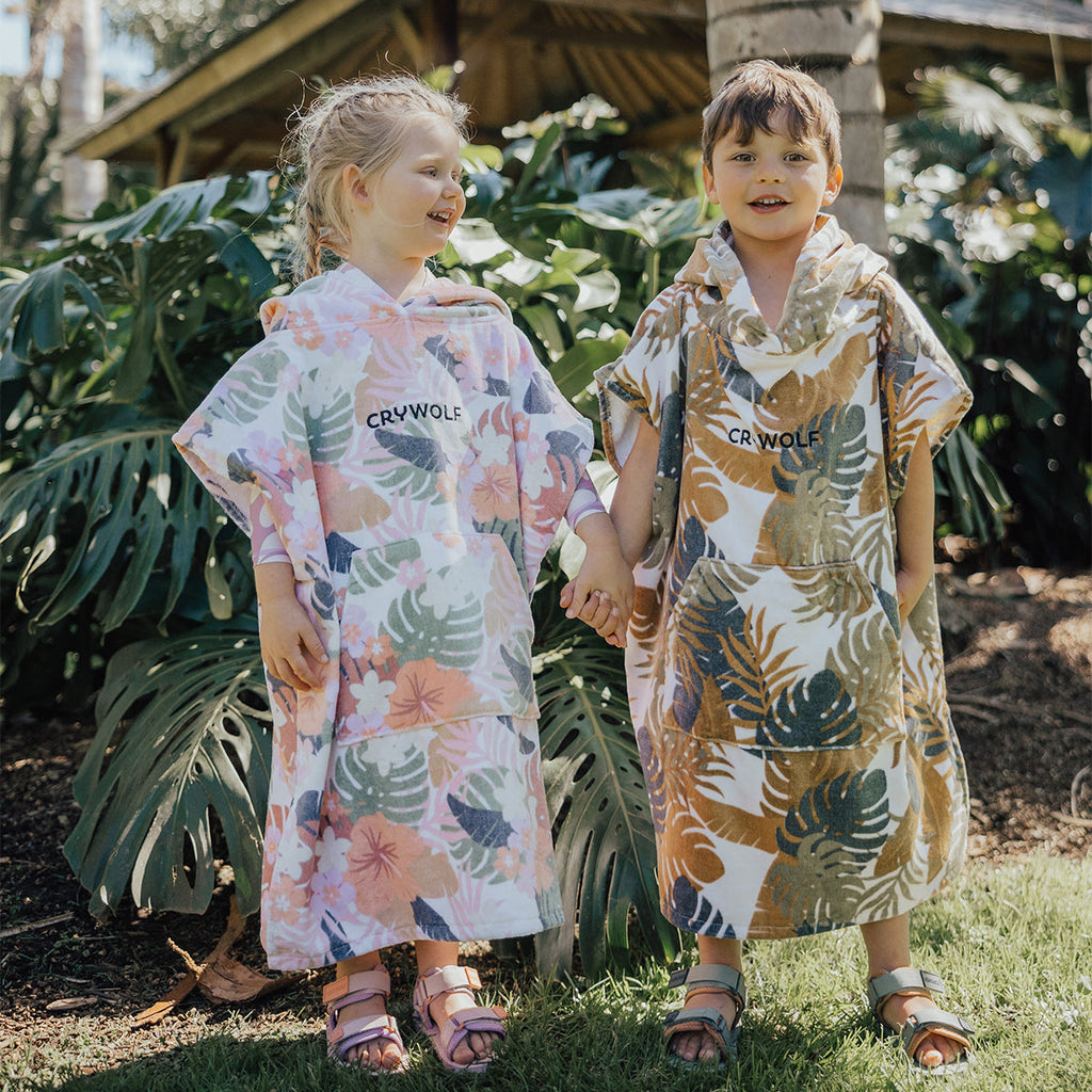 two children holding hands and enjoying the outdoors. They are wearing CryWolf's hooded towels.