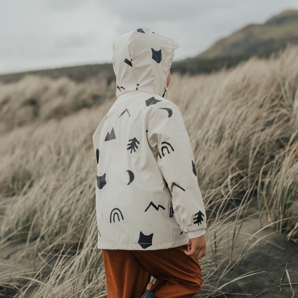 A child walking in a field wearing a Crywolf Happy Camper Play Jacket in White Colour