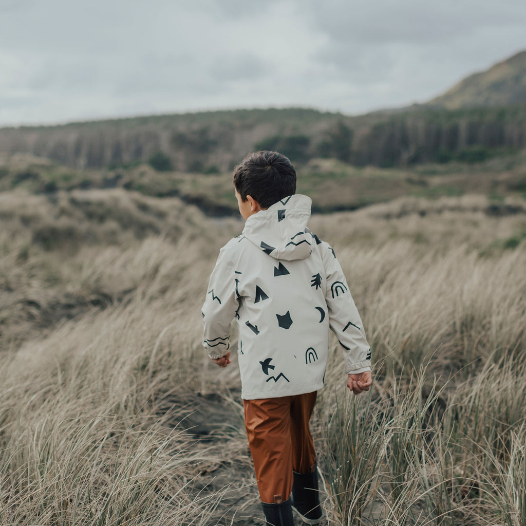 A boy walking in a field wearing a Crywolf Happy Camper Play Jacket