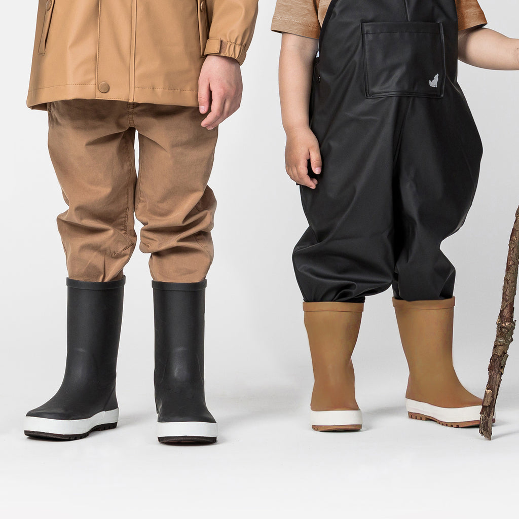 Two children wearing Crywolf rain boots in black and tan colours